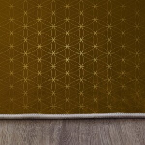 May include: A gold and brown patterned rug with a white border. The rug has a geometric design with a flower of life pattern.
