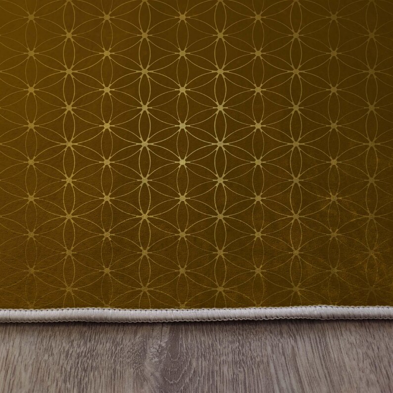 May include: A gold and brown patterned rug with a white border. The rug has a geometric design with a flower of life pattern.