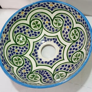 Peut inclure: Un évier en céramique blanche avec un bord bleu et un motif géométrique vert, bleu et jaune.