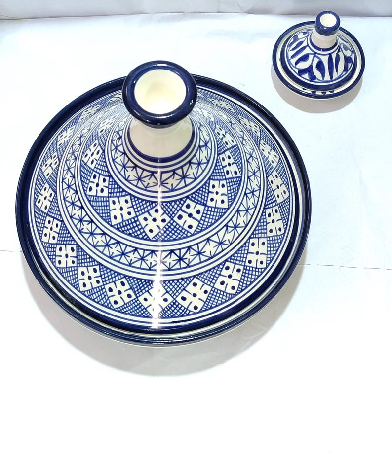 This traditional Moroccan tajine showcases the region's renowned ceramic artistry. The domed lid and wide, shallow base feature intricate geometric patterns in a classic blue and white color palette, making it a beautiful piece of Moroccan cookware .