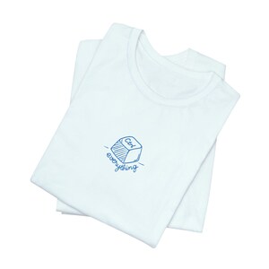 May include: Two white t-shirts are neatly folded, one on top of the other. The top shirt has a blue graphic of a cube with "Ctrl" on it, and the word "everything" below. The shirts are made of a soft, likely cotton material.