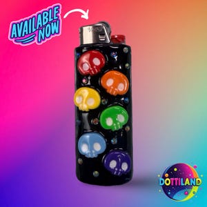 K&ouml;nnte beinhalten: Schwarzes Feuerzeug, verziert mit bunten Totenkopfmotiven. Die Totenk&ouml;pfe sind rot, orange, gelb, gr&uuml;n, blau und lila. Das Feuerzeug tr&auml;gt den Text "AVAILABLE NOW" in einer Sprechblase.