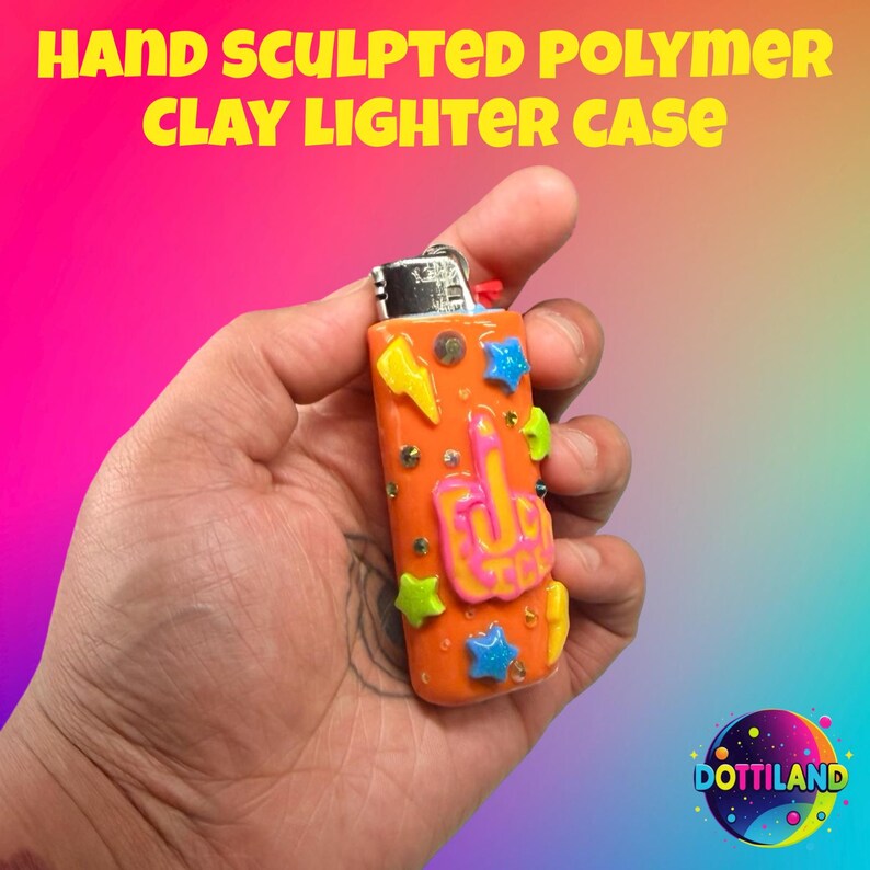May include: Hand-sculpted polymer clay lighter case in orange, decorated with colorful stars, lightning bolts, and a hand gesture. The text "HAND SCULPTED POLYMER CLAY LIGHTER CASE" is displayed at the top. The lighter case is held in a hand.