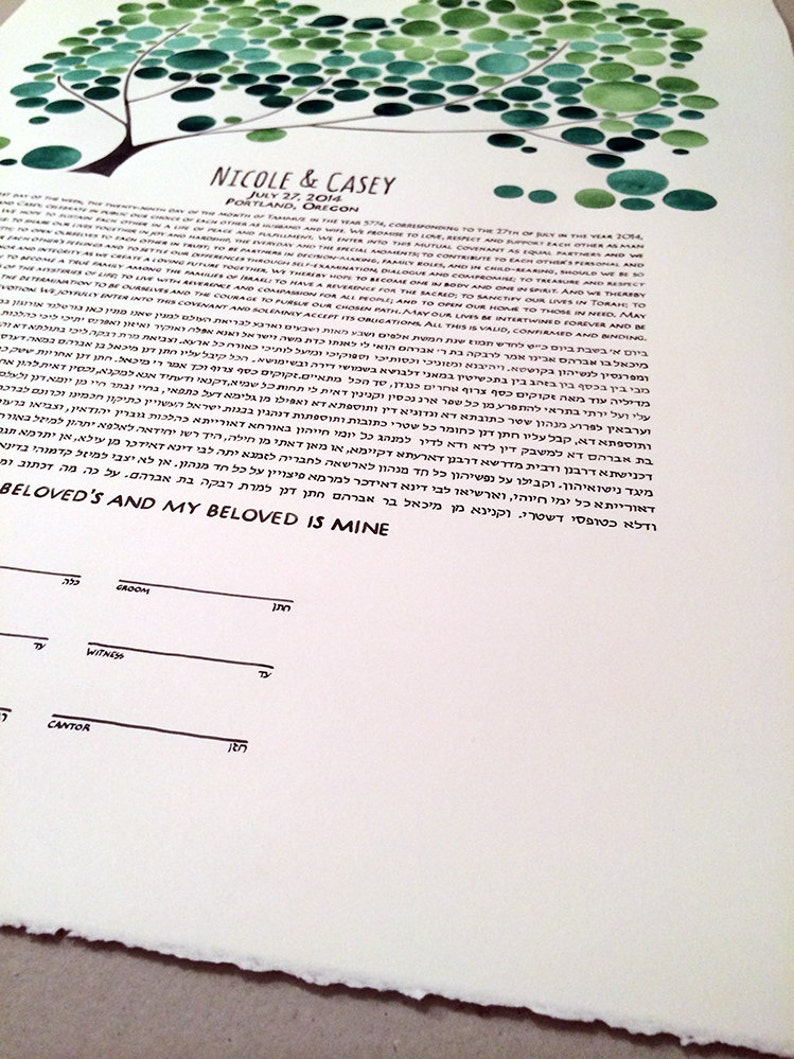 May include: A watercolor painting of a tree with green circles representing leaves. The text "NICOLE & CASEY" is written in black ink at the top of the page. Below the tree, the text "JULY 27, 2014" and "PORTLAND, OREGON" is written in black ink. The text below is in Hebrew.