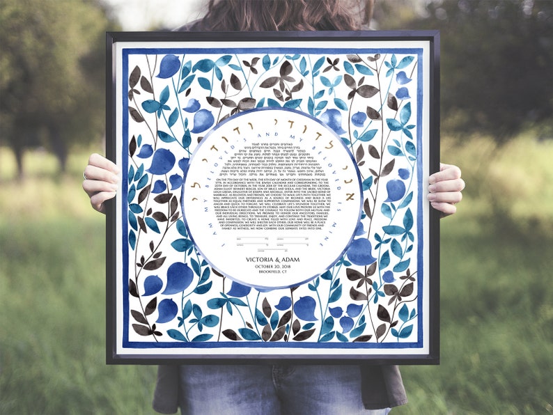 May include: A framed Jewish wedding ketubah with a blue and brown floral design. The ketubah text is in Hebrew and English. The couple's names, Victoria & Adam, and wedding date, October 28, 2018, are printed at the bottom.