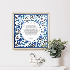 May include: A framed watercolor ketubah with a blue and brown floral design. The ketubah features a circle with Hebrew text and the names "Victoria & Adam" and the date "October 20, 2018".
