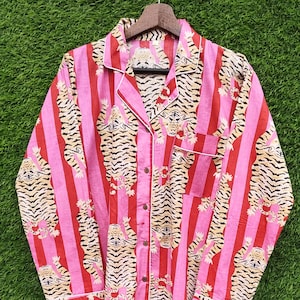 May include: Pink and red striped pajama top with a tiger print. The long-sleeved top has a button-down front, a chest pocket, and white trim. The tiger print features tan and black tigers.