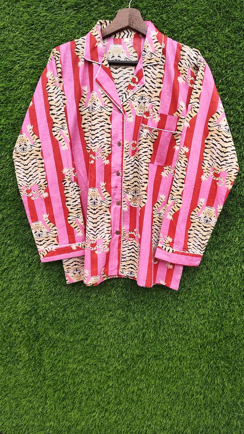 May include: Pink and red striped pajama top with a tiger print. The long-sleeved top has a button-down front, a chest pocket, and white trim. The tiger print features tan and black tigers.