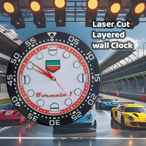May include: A round wall clock with a black bezel and a white face, featuring red hands and a Formula 1 logo. The clock has a layered design and the text "Laser Cut Layered wall Clock". The background shows race cars on a track.