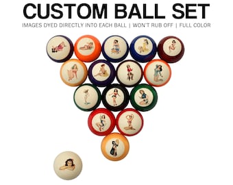 May include: A custom ball set with images dyed directly into each ball. The set includes 16 billiard balls, each featuring a different pin-up girl illustration. The balls are in various colors, including red, orange, blue, and green. The text "CUSTOM BALL SET" is at the top.