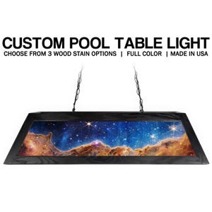 May include: A rectangular pool table light fixture with a black frame and a celestial image. The fixture is suspended by chains. Text on the image reads "CUSTOM POOL TABLE LIGHT" and "CHOOSE FROM 3 WOOD STAIN OPTIONS | FULL COLOR | MADE IN USA."