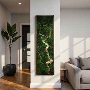 Op de afbeelding: Een rechthoekig kunstwerk voor aan de muur met een levendig groen mosontwerp en een lichtgekleurd, kronkelend takachtig element. Het kunstwerk is ingekaderd in een donkerbruine houten lijst, wat een natuurlijke uitstraling aan het interieur geeft.