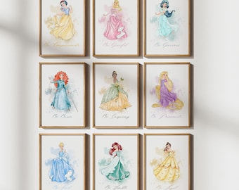 Op de afbeelding: Negen ingelijste aquarelprints met Disney-prinsessen in verschillende poses en jurken. Elke print heeft de naam van een prinses en een inspirerend woord eronder. De prints zitten in houten frames.
