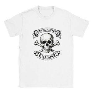 May include: White t-shirt featuring a black and white graphic of a skull and crossbones with the words "DEMOCRATIC REPUBLIC" above and "EST. 1680" below. The shirt also includes the phrases "Elected Captains - Equal Shares - Written Articles".
