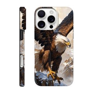 Peut inclure: Une coque de téléphone avec une image rapprochée d'un pygargue à tête blanche aux plumes brunes et blanches, perché sur un sommet de montagne enneigé. Les ailes de l'aigle sont déployées et il regarde vers la droite. L'arrière-plan est une image floue d'une chaîne de montagnes enneigée.