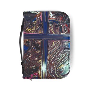May include: A rectangular wallet with a black strap, featuring an abstract art design. The wallet has a dark blue cross design over a background of swirling brushstrokes in shades of purple, pink, and gold.