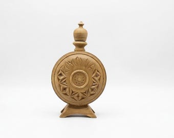 Könnte beinhalten: Eine hellbraune Holzflasche mit rundem Körper, engem Hals und abgerundetem Verschluss. Die Vorderseite zeigt ein geschnitztes Sternmuster um einen Mittelkreis, wobei das Wort ROMANIA in Großbuchstaben am oberen Rand eingraviert ist.