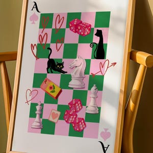 Op de afbeelding: Ingelijste kunstprint met een grillig ontwerp met een dambordpatroon in roze en groen. Het kunstwerk bevat speelkaartsymbolen, dobbelstenen, schaakstukken en katten silhouetten. De Aas van Schoppen is zichtbaar aan de boven- en onderkant van de print.