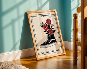 May include: A framed art print featuring a black and white high-top sneaker with red flowers and green leaves emerging from the top. The artwork is set against a cream background with a black border and is displayed in a wooden frame.