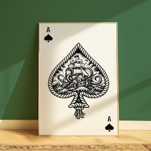 Puede incluir: Impresión artística enmarcada en blanco y negro que presenta un diseño de As de Picas. La forma de la pica está delineada con cuerda y contiene una ilustración detallada de un barco luchando contra un kraken. La carta tiene la letra "A" y un símbolo de pica arriba y abajo.