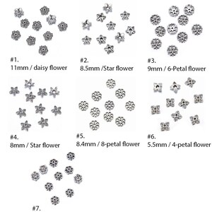 May include: Assortment of silver-toned metal flower-shaped embellishments. The embellishments are in various sizes and styles, including daisy, star, and 6-petal flower designs.