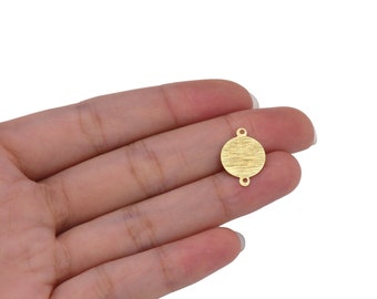 May include: Gold-toned metal circle charm with two jump rings. The circle has a textured surface.