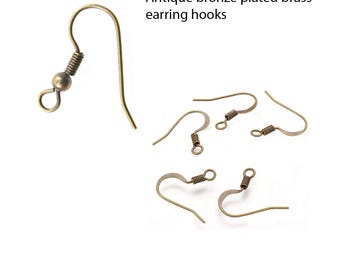 May include: Antique bronze plated brass earring hooks. The image shows several earring hooks in a warm, antique bronze color. The hooks have a simple, curved design with a small coil and a ball at the top. The text in the image says "Antique bronze plated brass earring hooks."