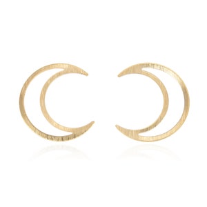 May include: A pair of gold crescent moon earrings. The earrings are made of a thin metal and have a brushed finish.