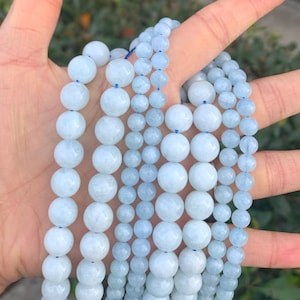 May include: A strand of light blue aquamarine beads, with different sizes of beads, arranged in rows.