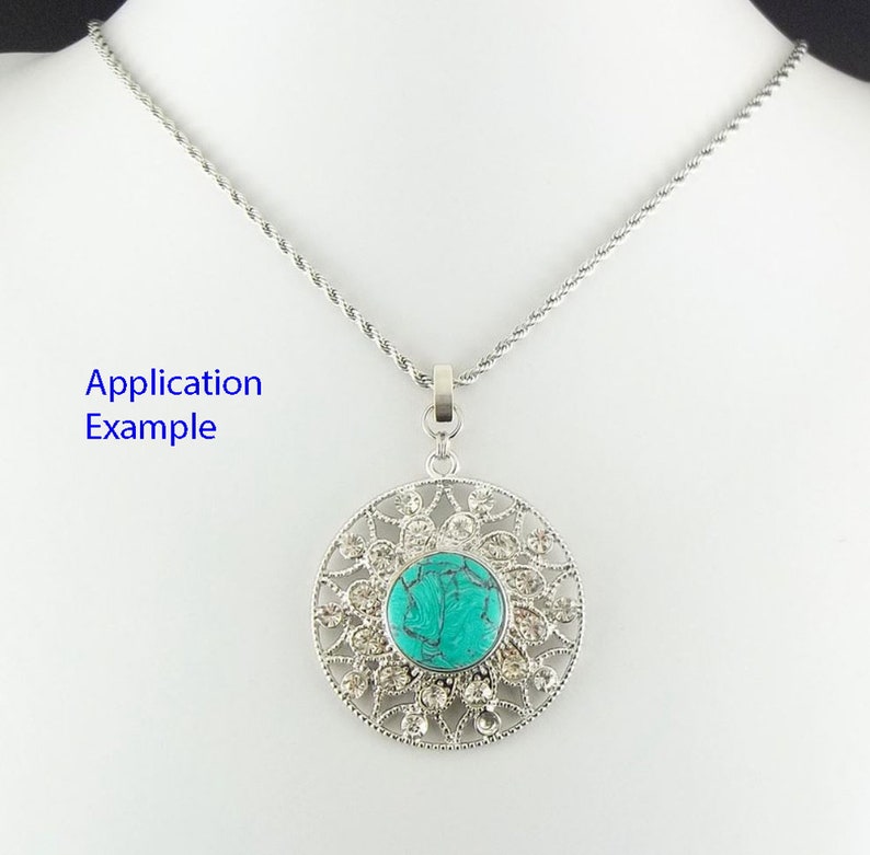 Puede incluir: Un collar de cadena de plata con un colgante de piedra turquesa. El colgante est&aacute; rodeado por un dise&ntilde;o de filigrana de plata con diamantes de imitaci&oacute;n transparentes.