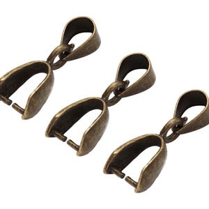 Op de afbeelding: Drie antiek bronzen hangerbeugels. Elke beugel heeft een lus aan de bovenkant en een U-vormige sluiting aan de onderkant met twee kleine pinnen. De beugels zijn ontworpen voor het maken van sieraden en knutselen.