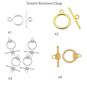 May include: Four different styles of tarnish resistant clasps for jewelry making. Clasps are silver and gold in color. #1 is a simple silver toggle clasp. #2 is a gold toggle clasp. #3 is a silver toggle clasp with a decorative flower design. #4 is a gold toggle clasp with a decorative flower design.