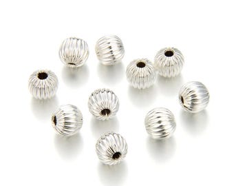 May include: A group of ten silver-toned round beads with a textured surface. The beads are scattered on a white background.