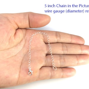 May include: A 5 inch silver chain, shown in a hand for size reference.  The chain is made of small, linked circles.