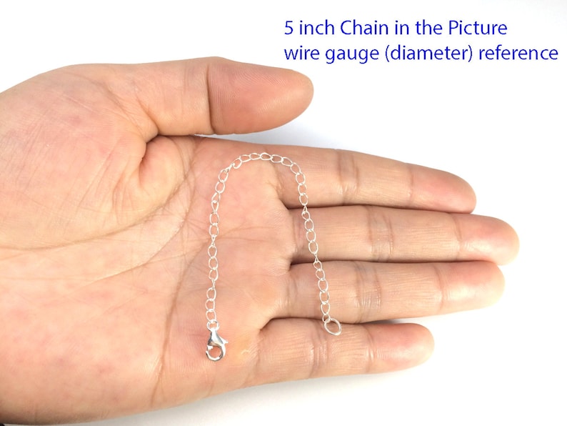 May include: A 5 inch silver chain, shown in a hand for size reference.  The chain is made of small, linked circles.