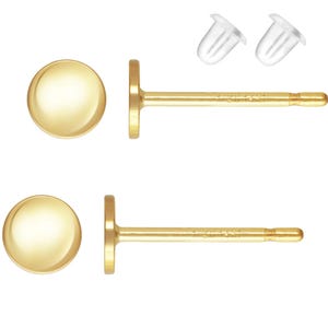 Könnte beinhalten: Ein Paar goldene Ohrstecker mit runden, glatten Oberseiten. Die Ohrringe werden mit einem Paar transparenten Silikon-Rücken geliefert.
