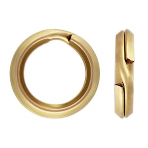May include: Gold-toned metal jump ring with a slightly open design. The ring is shown from two angles.