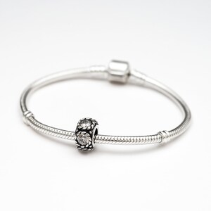 May include: A silver charm bracelet with a silver charm featuring clear cubic zirconia stones.