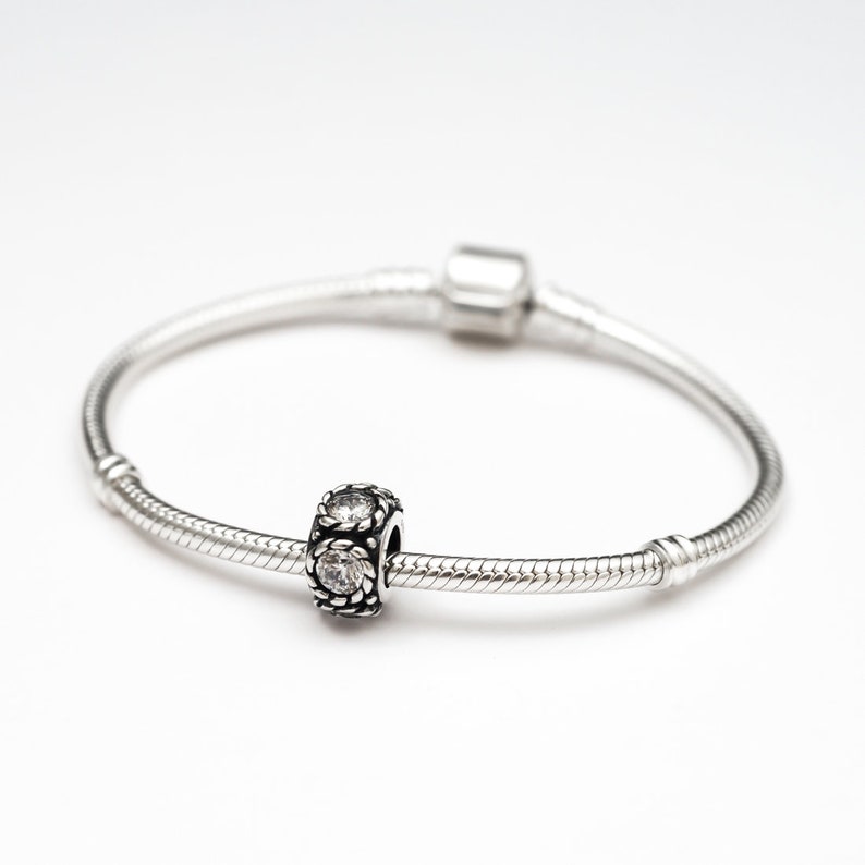 May include: A silver charm bracelet with a silver charm featuring clear cubic zirconia stones.