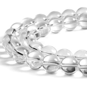 May include: A strand of clear quartz crystal beads. The beads are round and smooth, and they are strung on a clear elastic cord.