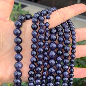 May include: A set of eight strands of dark blue gemstone beads. The beads are round and have a speckled, glittery appearance.
