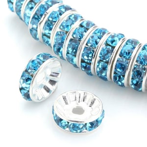 May include: Silver tone bead spacers with a row of turquoise blue rhinestones around the edge.
