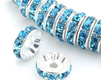 May include: Silver tone bead spacers with a row of turquoise blue rhinestones around the edge.
