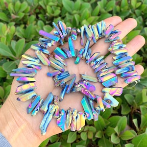 May include: A strand of iridescent blue, purple, and gold crystal point beads. The beads are faceted and have a rough, natural texture.