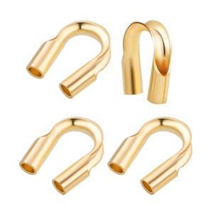 May include: Four gold-colored metal cable end crimp connectors. Each connector has a U-shaped opening and a rounded end.