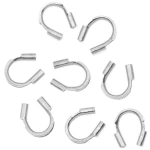 May include: A collection of silver-colored, U-shaped jewelry findings. Each finding has a curved body with a small, cylindrical tube at each end. The findings are scattered against a white background, suggesting a craft or jewelry-making theme.