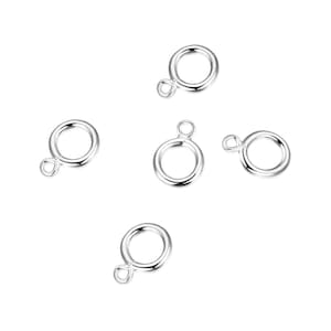 Puede incluir: Cinco anillos de salto de plata con un pequeño bucle en un lado. Los anillos tienen un diámetro de aproximadamente 1,25 cm.