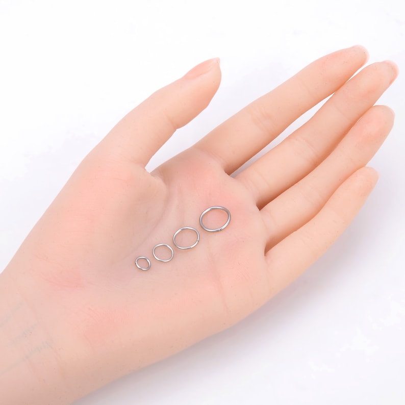 May include: Five silver seamless hoop rings of different sizes, displayed on a hand.