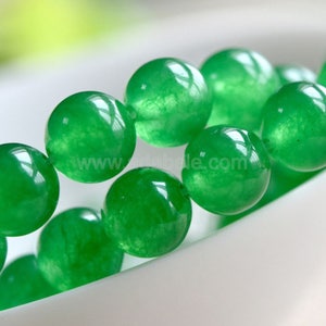 May include: A strand of round, green jade beads. The beads are smooth and polished, with a slight sheen.