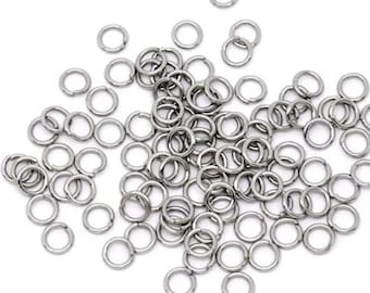 May include: A large pile of silver jump rings, a type of jewelry finding used for connecting chains, cords, and other jewelry components.
